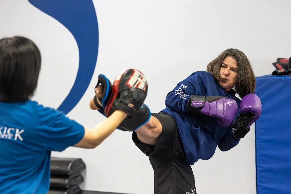 Woman performing a kick during kickboxing training at a martial arts school