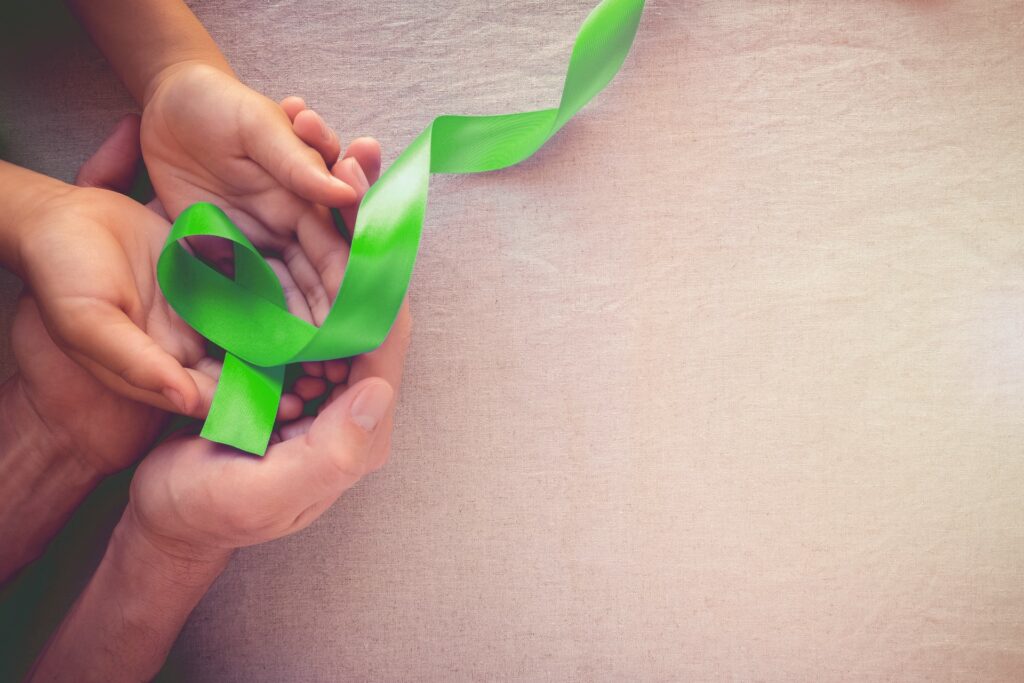 mental health green ribbon in adult child hands