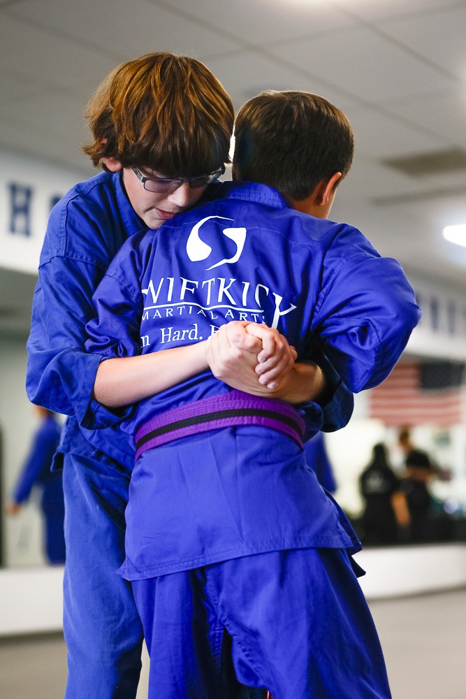 two martial arts students grappling wrestling to ground