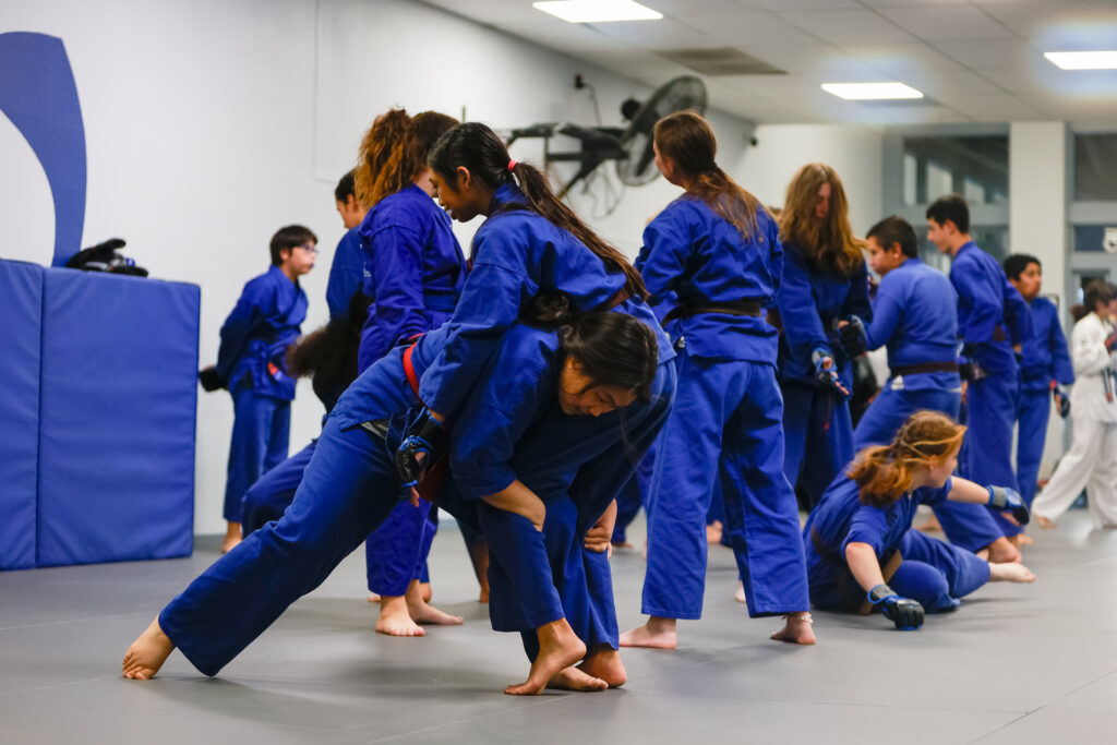 Girl performing a double leg take down on another student