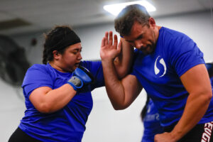 Woman performing muay thai concepts on larger man