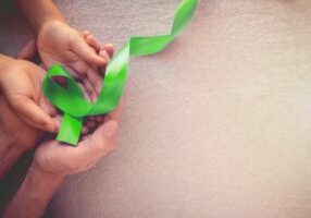 mental health green ribbon in adult child hands