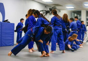 Girl performing a double leg take down on another student